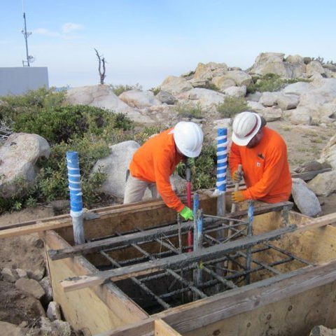 Crew setting rebar for a remote station foundation